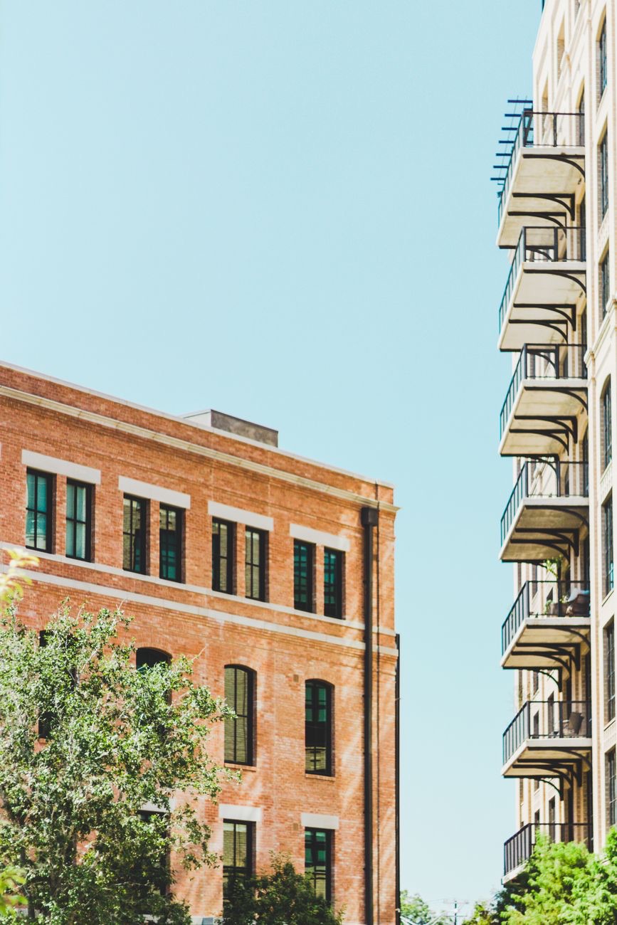 Brick lofts beside a balconied apartment building under a clear sky