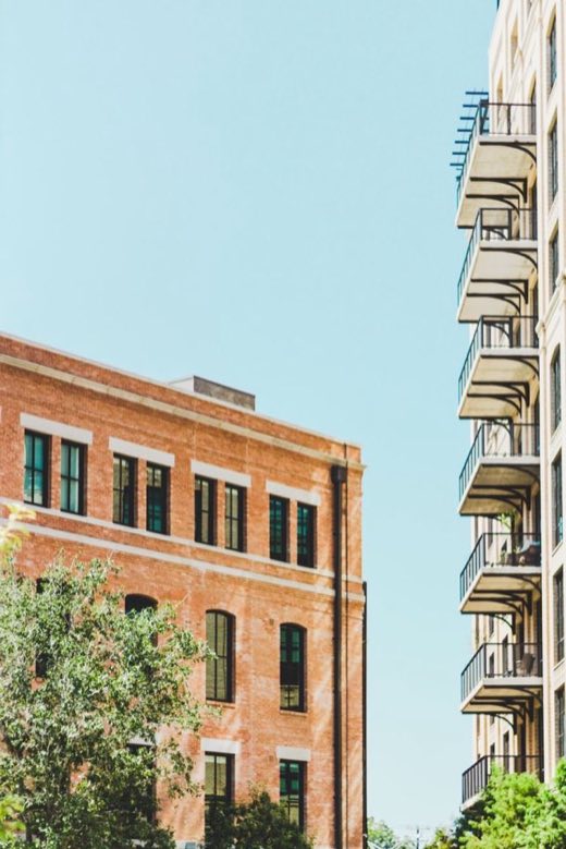 Brick lofts beside a balconied apartment building under a clear sky