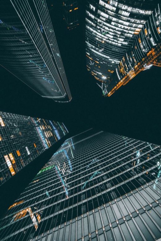 Looking up between illuminated glass high-rise towers at night