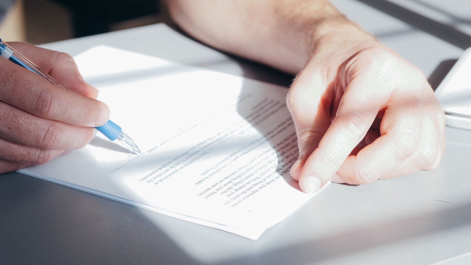A pen held over the pages of a printed document