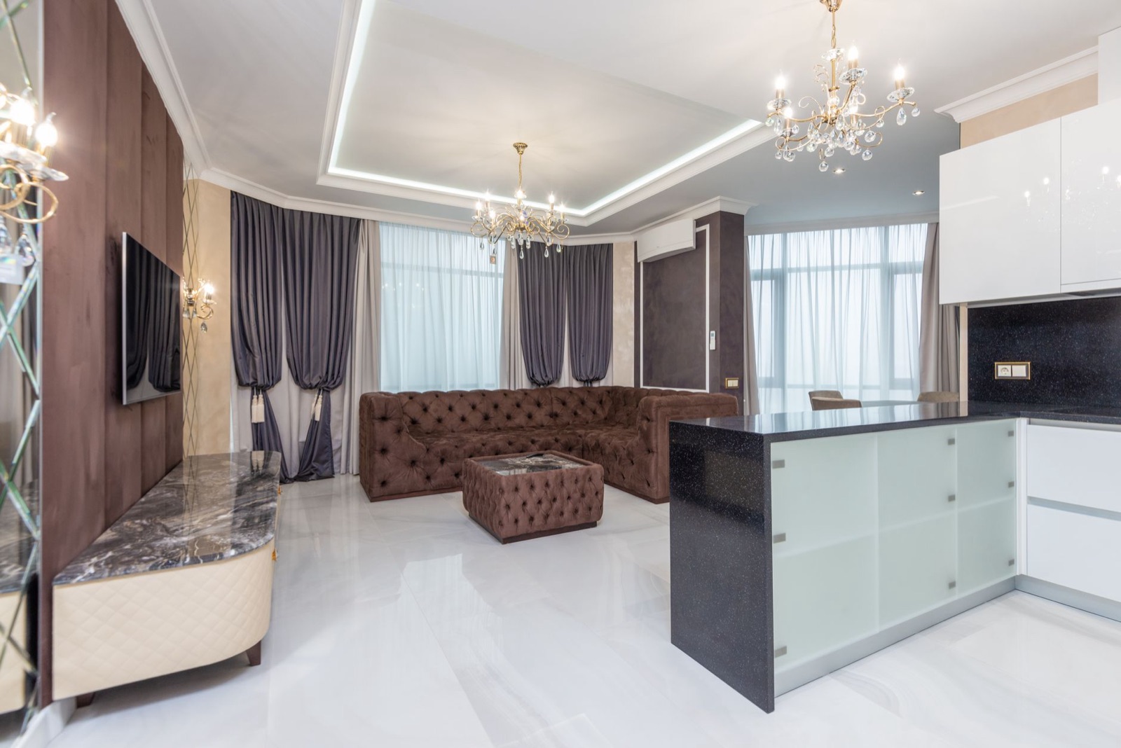 Living room with chandeliers, velvet seating, and a stone island
