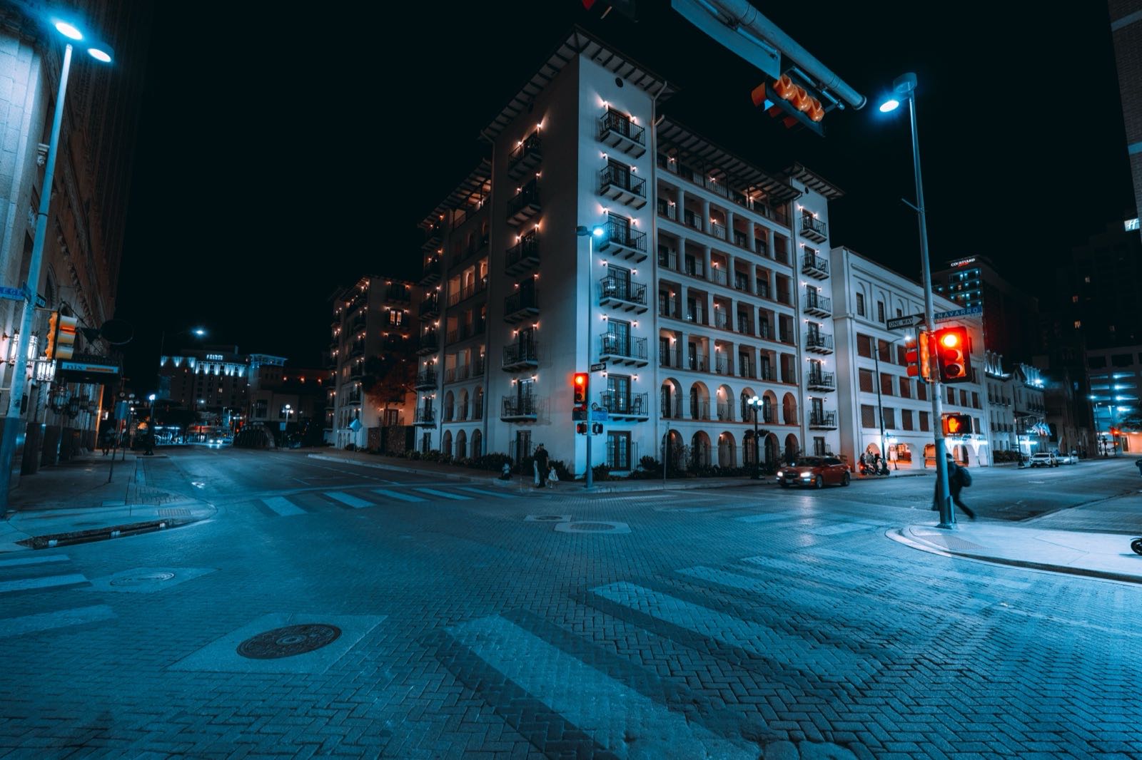 Lit balconies of a white mid-rise on a downtown San Antonio corner at night