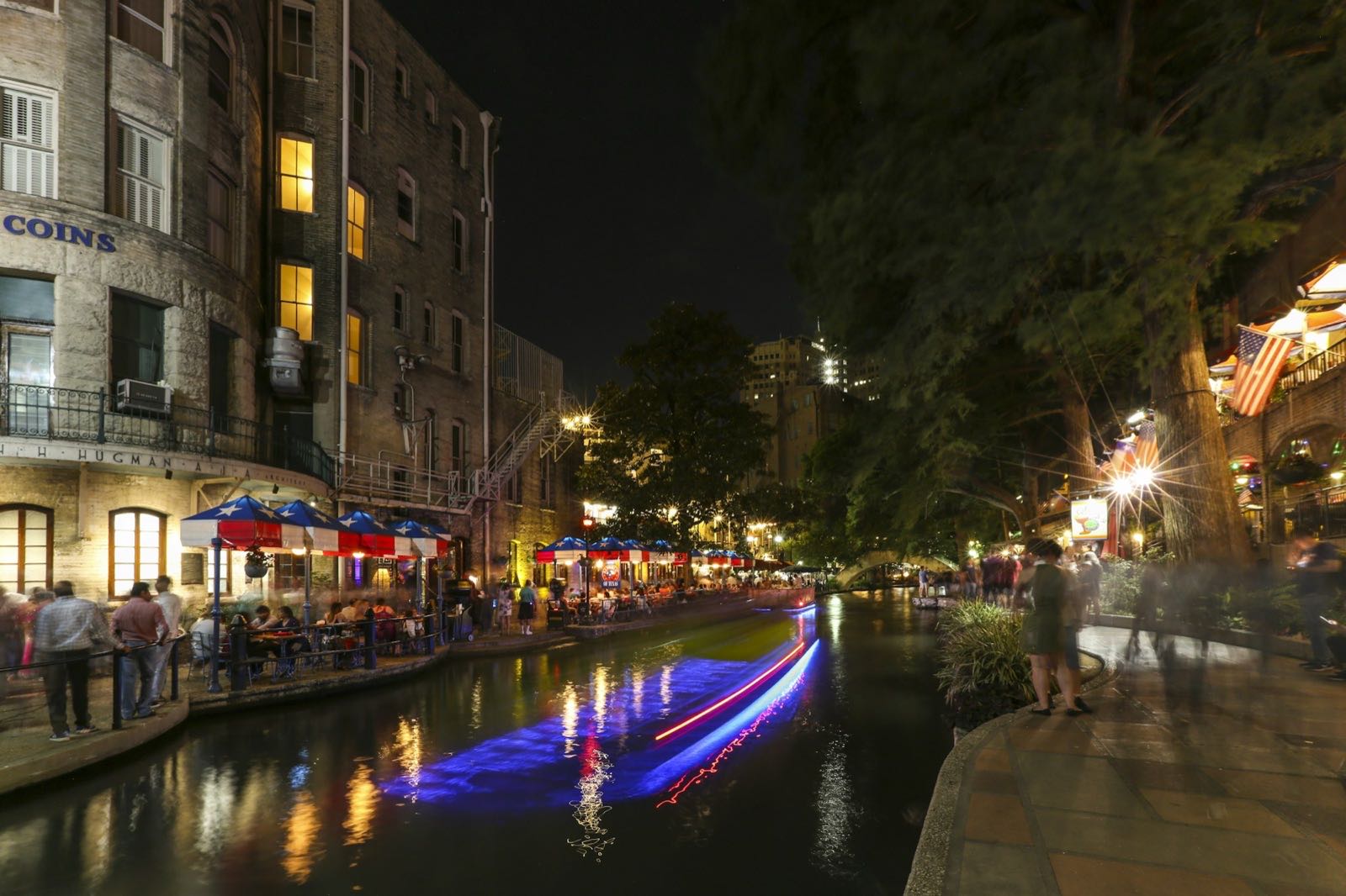 Light trails of a river barge passing River Walk terraces at night