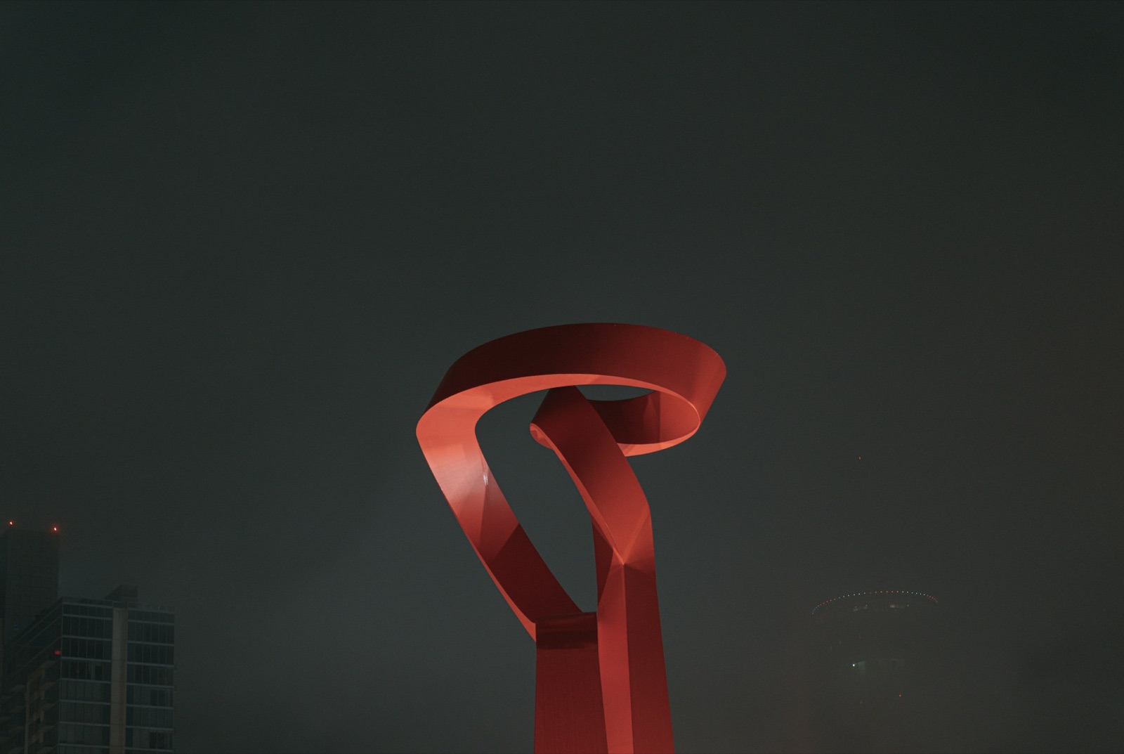 Red sculpture glowing over a downtown San Antonio intersection at night